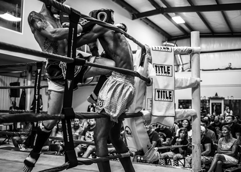 Combat de muay-thaï dans le coin d’un ring, en noir et blanc